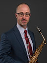 Eric Lau, an adult man wearing a suit and holding a saxophone